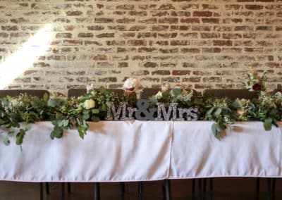 Head table greenery garland that includes eucalyptus, baby's breath, and white roses.
