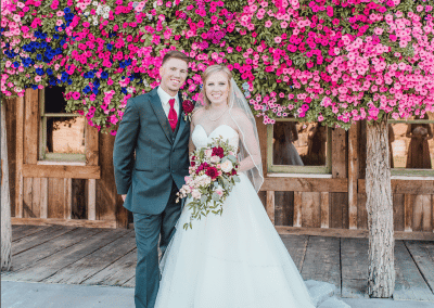 Bride and groom standing while bride holding her bouquet that has burgundy dahlias, pink mini roses, lisianthus, baby's breath, and eucalyptus.