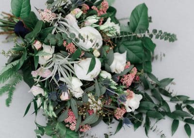 Beautiful bridal bouquet with ivory roses, ivory peonies, thistle, rice flower, air plants, lisianthus, eucalyptus, greenery, and ferns.