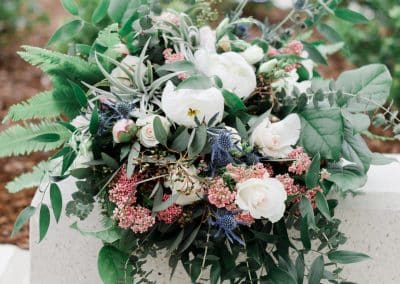 Beautiful bridal bouquet with ivory roses, ivory peonies, thistle, rice flower, eucalyptus, greenery, and ferns.