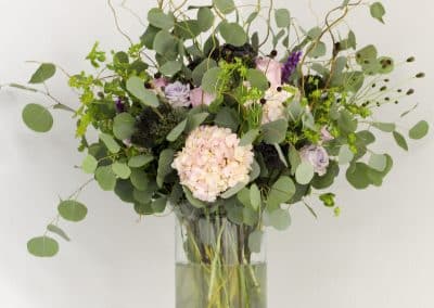 Large centerpiece with hydrangea, pink roses, curly willow, and eucalyptus.